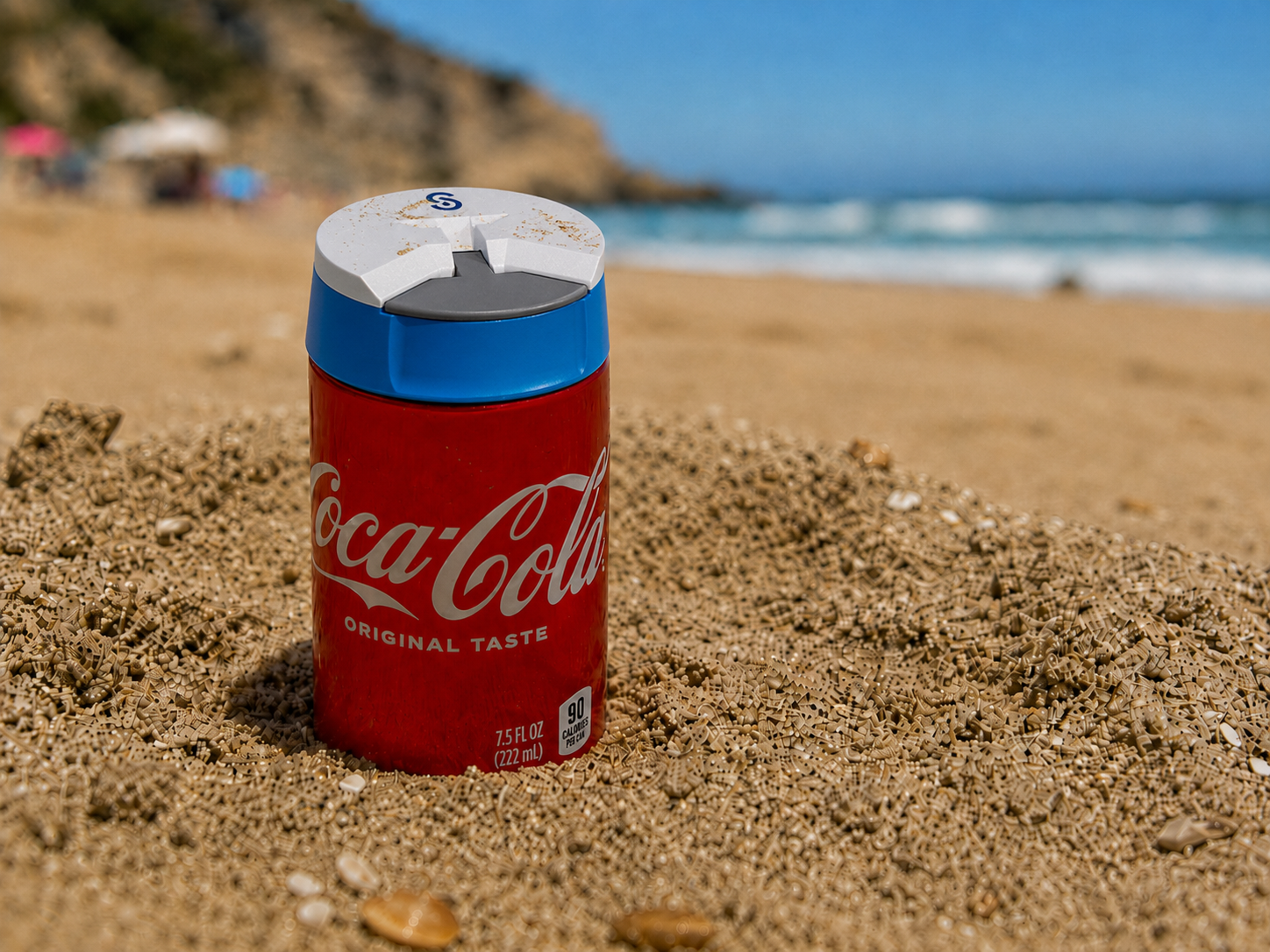Coca-Cola can with SIpivo sip safe guard on top on a sandy beach with ocean and cliffs in the background
